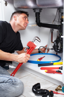 Garland plumber prepares to fix sink drain with a pipe wrench in hand